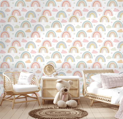 Nursery room with rainbow and cloud patterned wallpaper, wicker furniture, and a teddy bear.
