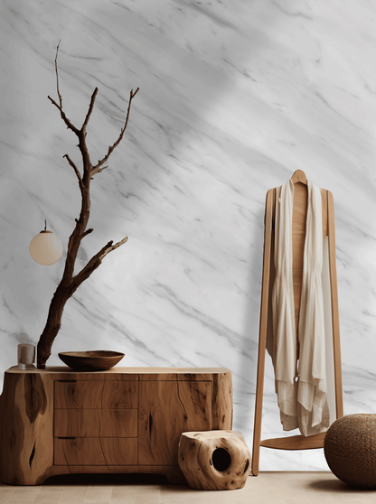 Wooden dresser with a branch and bowl against a marble wall.