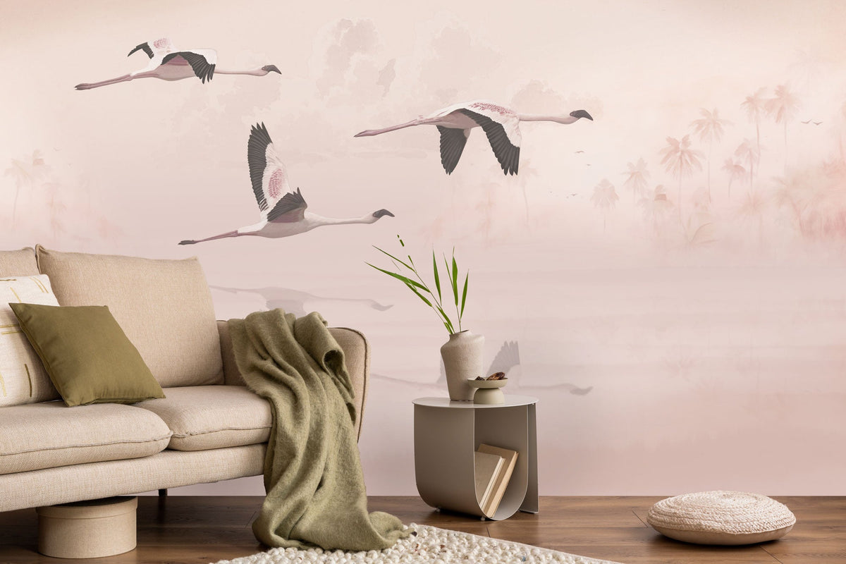 A section of wallpaper featuring a mural of flamingos flying over water, with a sofa, cushions, and decorative items in the foreground.