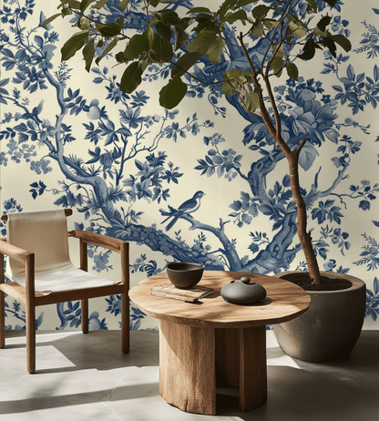 Room interior with wooden chair, table, and potted plant against a wall with blue floral wallpaper.